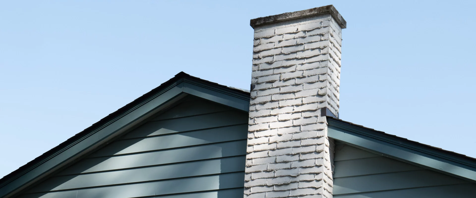 greyish blue house with a white brick chimney